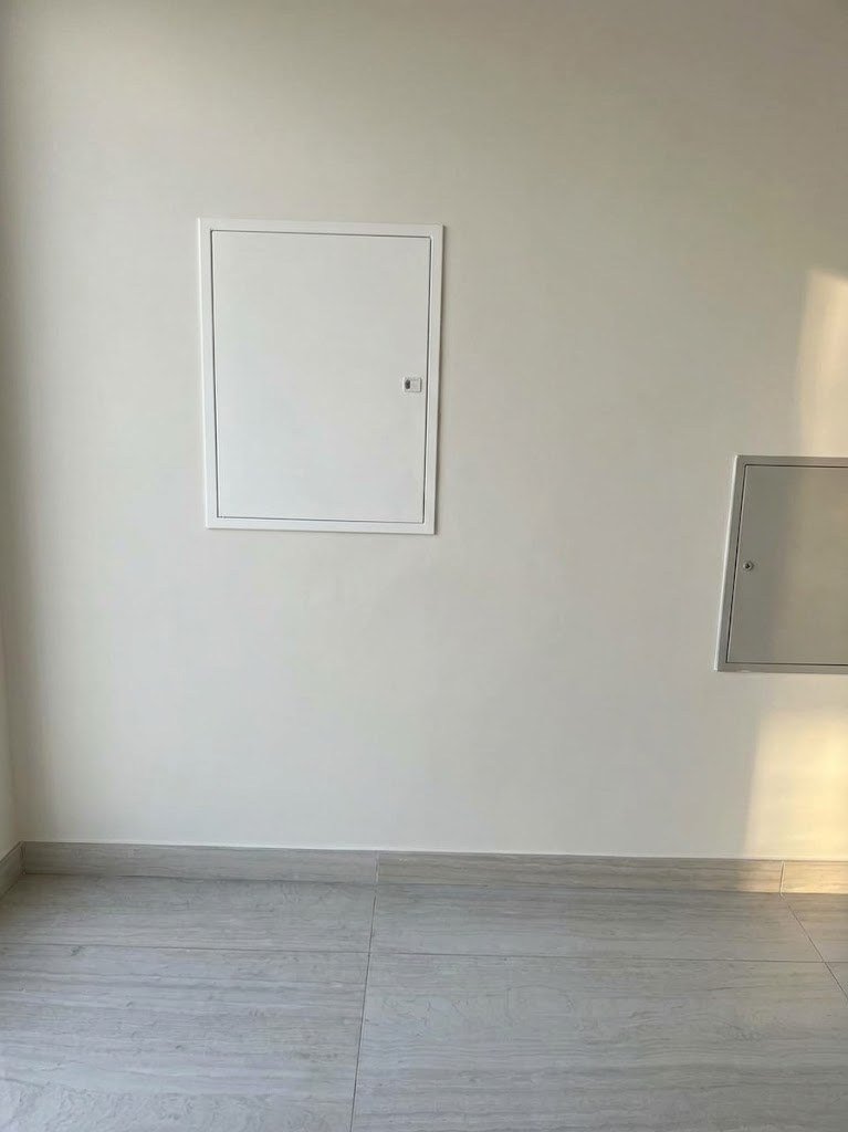 Distribution board behind a flush white door in a finished villa